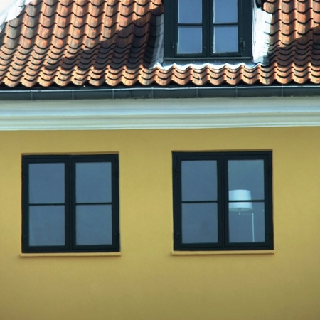 Klassisk gul facade med sorte vinduesrammer malet med KEIM Soldalit silikatmaling