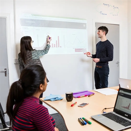 Team arbejder med præsentation på væg malet med Smarter Surfaces Mat Whiteboard Maling